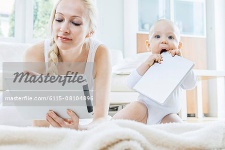 Mother with digital tablet alongside baby