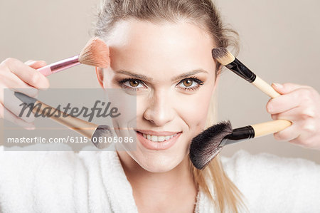 Young woman holding makeup brushes