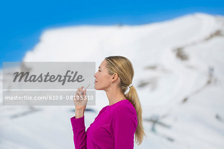 Beautiful woman applying lip balm on her lips, Crans-Montana, Swiss Alps, Switzerland