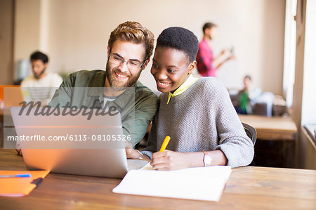 Smiling creative business people using laptop and brainstorming