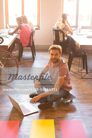 Portrait creative businessman working on laptop on floor