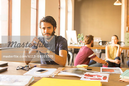 Portrait confident creative businessman working with proofs in office