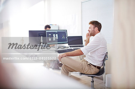 Architect talking on cell phone at computer in office