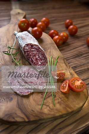 Close up of red sausage stick with tomatoes on a chopping board, Germany Close up of red sausage stick with tomatoes on a chopping board, Germany