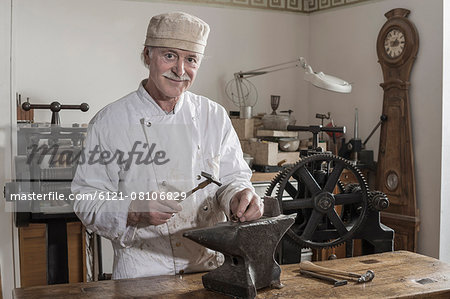 Senior craftsman shaping of copper ring at workshop, Bavaria, Germany