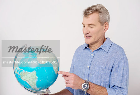 Senior man pointing his finger on globe