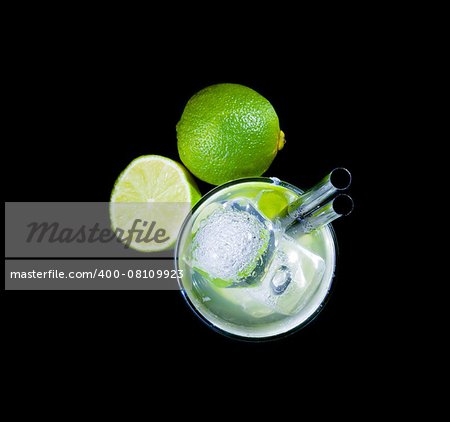 top of view of glasses with cocktail and ice near lime on black background, disco club atmosphere