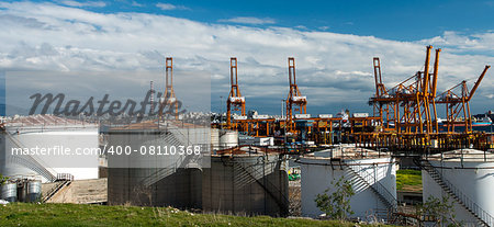 Oil tanks in the port with loading kranes and tankers on the background