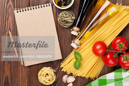 Italian food cooking ingredients. Pasta, tomatoes, basil. Top view with notepad for copy space