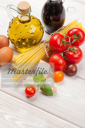 Italian food cooking ingredients. Pasta, tomatoes, basil on wooden table