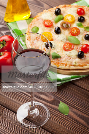 Pizza and red wine glass on wooden table background