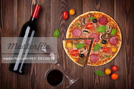 Pizza and red wine on wooden table background. Top view