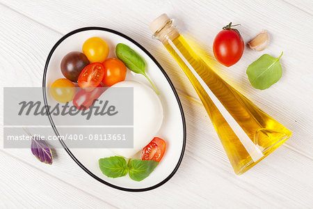 Mozzarella, tomatoes, basil and olive oil on wooden table