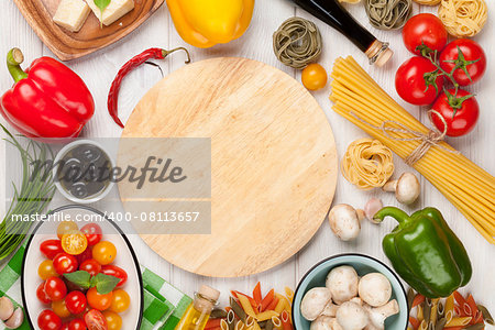 Italian food cooking ingredients. Pasta, vegetables, spices. Top view with cutting board for copy space