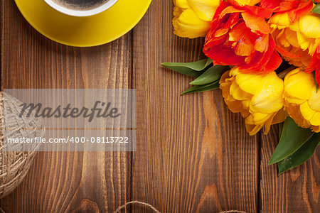 Colorful tulips bouquet and coffee cup on wooden table. Top view with copy space