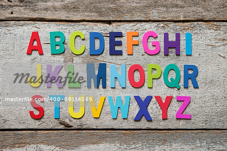Colorful wooden English alphabet set on grunge wooden background.