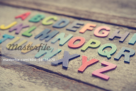 Colorful wooden English alphabet set on grunge wooden background, focus on alphabet X.