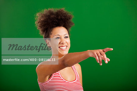 Happy African woman pointing to something over a green background