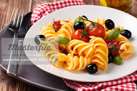 Italian pasta with cherry tomatoes, black olives and basil.