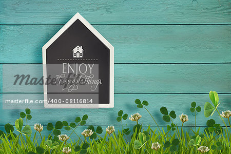 House shaped chalkboard and grass on wooden background