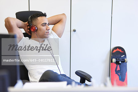 Young businessman relaxing and listening to headphones in office