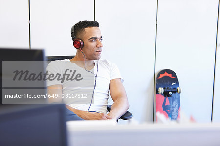 Young businessman listening to headphones in office