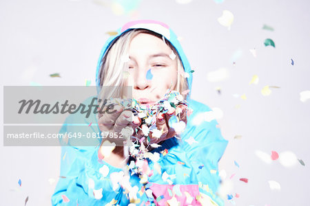 Studio portrait of young woman blowing confetti