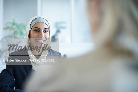 Over shoulder view of young businesswoman chatting to colleague in office