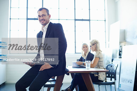 Portrait of mature businessman sitting on office desk