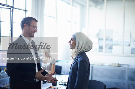 Mature businessman talking to young businesswoman in office Mature businessman talking to young businesswoman in office