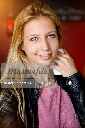 Portrait of young woman holding smartphone in cafe