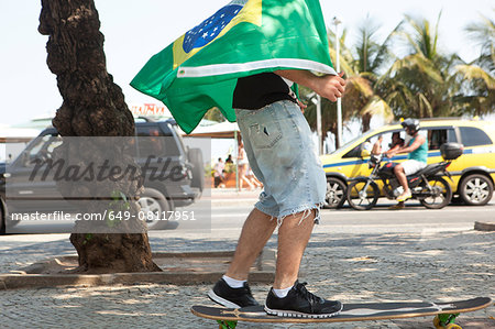 Young man skateboarding wrapped in Brazilian flag, Copacabana, Rio De Janeiro, Brazil