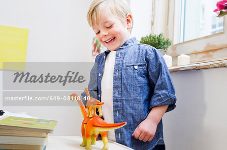 Boy playing with toy dinosaurs at home