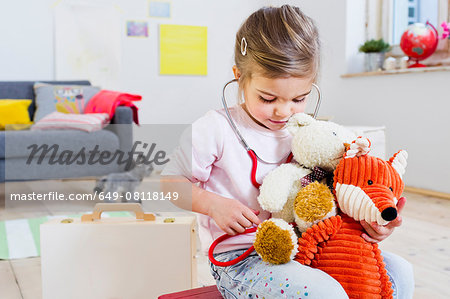 Girl playing doctor to soft toys Girl playing doctor to soft toys