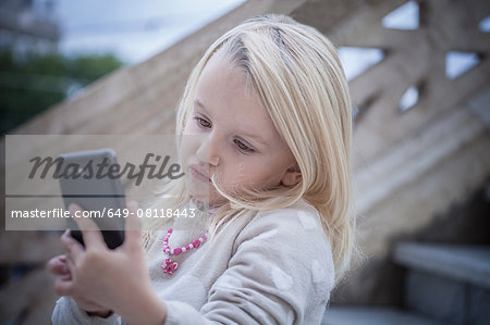 Confused young girl on stairway using smartphone, Cagliari, Sardinia, Italy