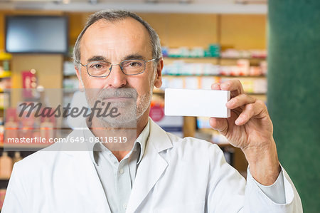Portrait of pharmacist holding up medicine in pharmacy