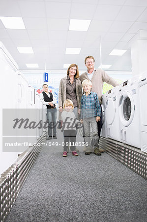 Portrait of family with two children browsing washing machines in electronics store