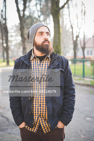 Portrait of mid adult man, standing in park, hands in pockets