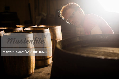 Young man working in cooperage with whisky casks