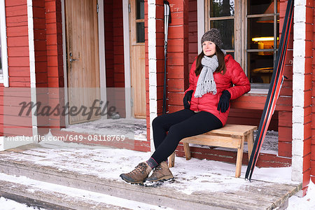 Portrait of young female skier sitting in cabin porch, Posio, Lapland, Finland