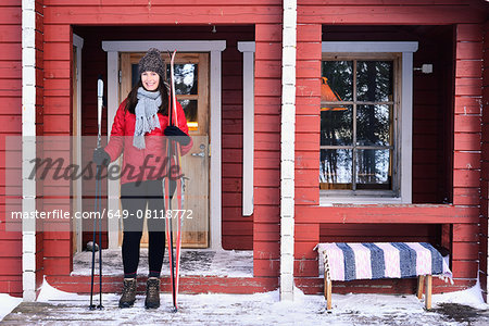 Portrait of young female skier on cabin porch, Posio, Lapland, Finland