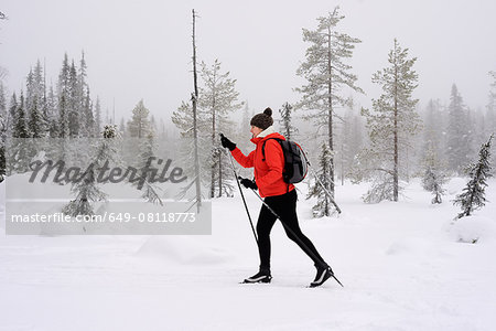 Young woman nordic walking in snow covered forest, Posio, Lapland, Finland