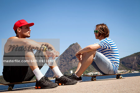 Two men sitting on skateboards, relaxing