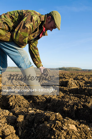 Farmers inspecting soil in ploughed field