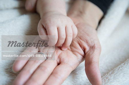 Baby boy's hand resting on mother's hand, close-up
