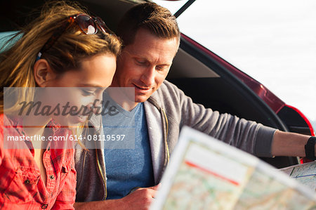 Couple reading map behind vehicle