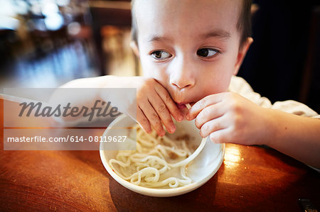 Boy eating noodles in restaurant