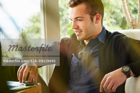 Portrait of man sitting on floor using laptop