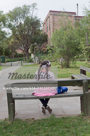 Young girl sitting on bench, rear view