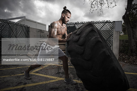 Male boxer training with truck tyre in yard